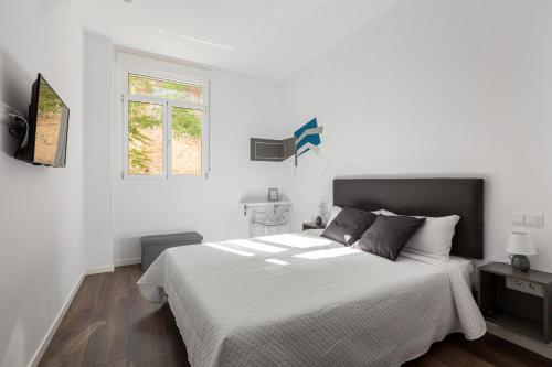 a white bedroom with a large bed and a window at Ronda9 central suites in Madrid