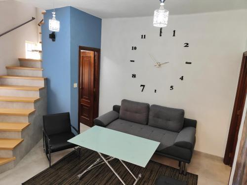 ein Wohnzimmer mit einem Sofa und einer Uhr an der Wand in der Unterkunft Alójate en Vigo! Casita bien equipada in Vigo