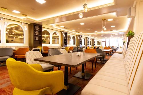 a restaurant with a table and yellow chairs at Admiral Hotel - Ultra All Inclusive & Private Beach in Golden Sands