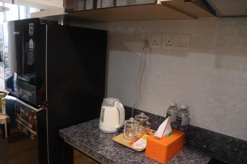 a kitchen with a black refrigerator and a counter with a toaster at Galeno Pollux Habibie in Batam Center