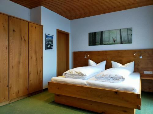 1 dormitorio con cama de madera y almohadas blancas en Pension Edelweiss, en Damüls