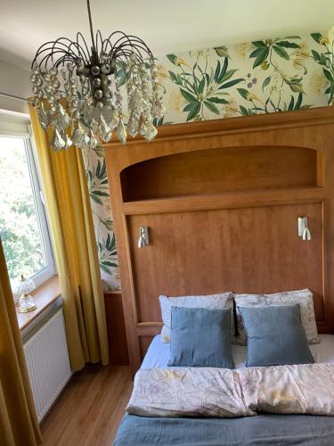 een slaapkamer met een bed met een houten hoofdeinde en een kroonluchter bij Bellis Apartment in Szczecin