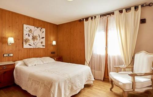um quarto com uma cama, uma cadeira e uma janela em Hostal Vidaller em Bielsa