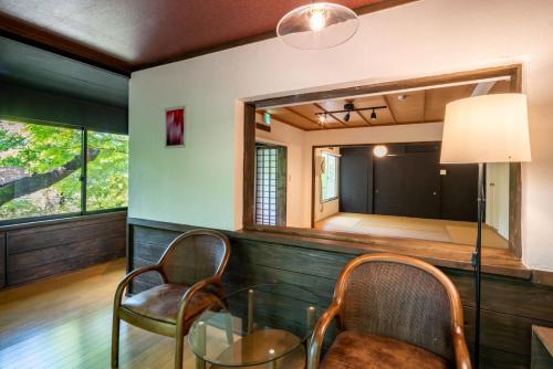 Habitación con mesa de cristal, sillas y espejo. en 森の宿り 那須別邸まるやま en Nasu