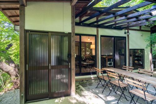 a patio with a wooden door and a table and chairs at 森の宿り 那須別邸まるやま in Nasu