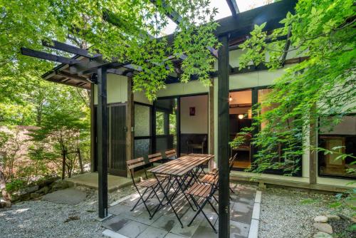 a house with a wooden table and chairs on a patio at 森の宿り 那須別邸まるやま in Nasu