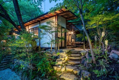 a house in the woods with a stone path leading to it at 森の宿り 那須別邸まるやま in Nasu