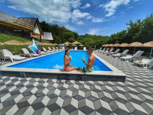 two children sitting next to a swimming pool at Etno Village Dolina Sreće in Vitez