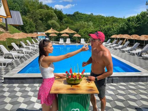 a man and a woman drinking wine at a table by a pool at Etno Village Dolina Sreće in Vitez