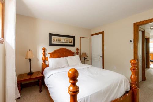- une chambre avec un grand lit en bois et des draps blancs dans l'établissement The Mont-Tremblant Hideaway by InstantSuites, à Mont-Tremblant