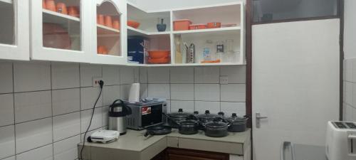 una cocina con armarios blancos y una encimera con ollas en Lyneks Cosy Apartment, en Mombasa