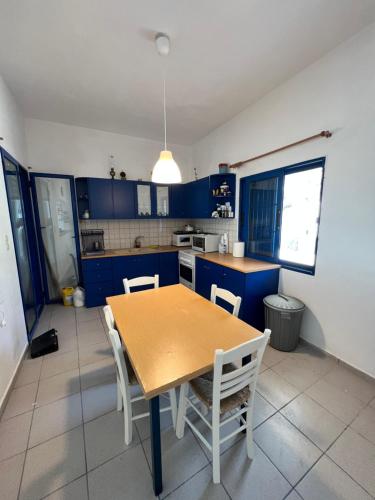 una cocina con armarios azules y una mesa y sillas de madera. en Comfortable house with seaview in Donousa en Donoussa
