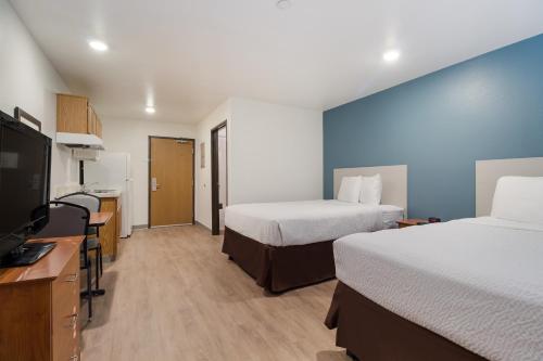a hotel room with two beds and a flat screen tv at WoodSpring Suites Houston I-45 Airtex in Houston