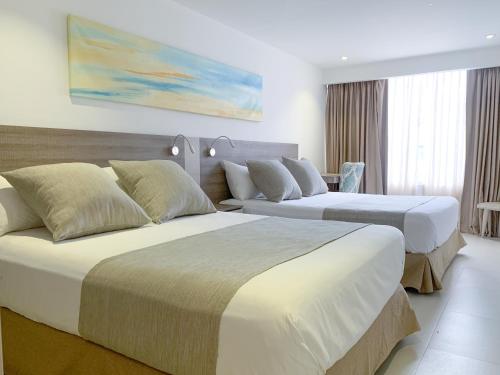 a hotel room with two beds and a couch at Hotel 1525 By GEH Suites in Santa Marta