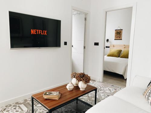 a living room with a couch and a tv on a wall at Estudio 33 in San Juan de la Arena