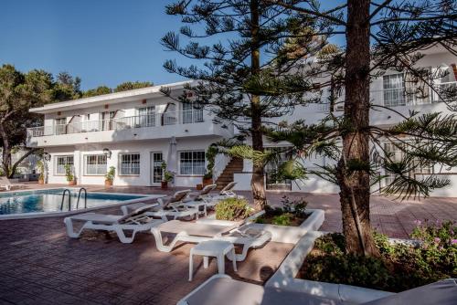 un complejo con piscina, mesas y un edificio en Hostal Es Pi - Emar Hotels en Playa Migjorn