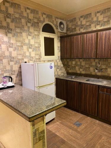 a kitchen with a white refrigerator and wooden cabinets at فندق ديوان اليمامة in Taif
