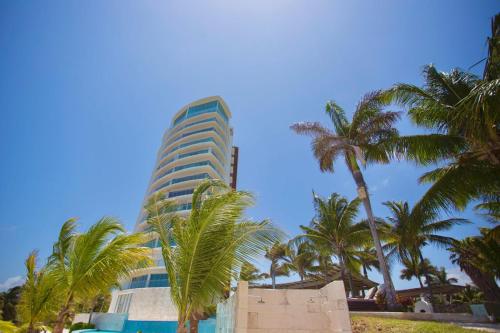a tall building with palm trees in front of it at Fabuloso departamento de lujo frente al mar in Cancún