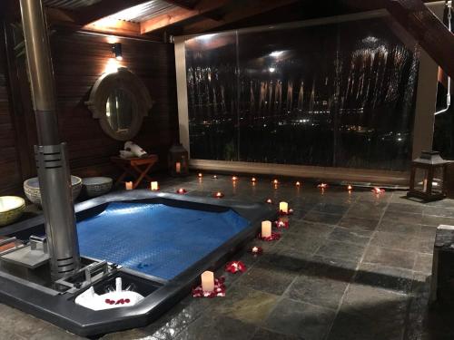 克尼斯納的住宿－Knysna Lodge - Self Catering Unit with Woodfired Hot Tub，一间带蜡烛的游泳池的房间和一间带游泳池的房间