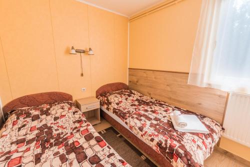 Habitación con 2 camas en una habitación con ventana en Boglárka Apartmanház, en Mezőkövesd