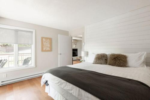 a white bedroom with a large bed and a window at The Outlook over Lac -Tremblant by Instant Suites in Mont-Tremblant