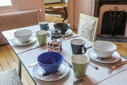 une table avec quatre tasses et soucoupes dessus dans l'établissement Artists' studio on the roofs of Montmartre - Welkeys, à Paris