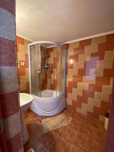 a bathroom with a shower with a toilet and a sink at Pensiunea Martuca in Şurdeşti