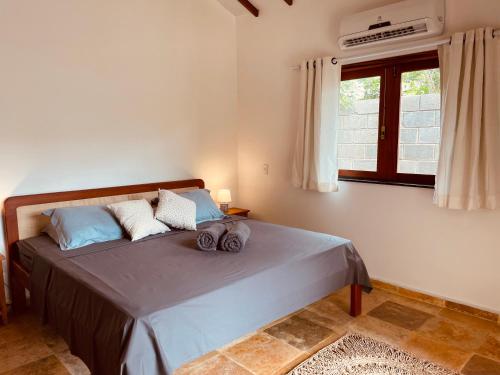 um quarto com uma cama com almofadas azuis e uma janela em Chales Barra Grande em Barra Grande