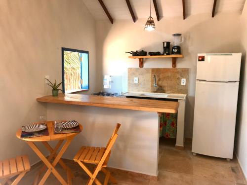 uma cozinha com um balcão, um frigorífico e uma mesa em Chales Barra Grande em Barra Grande