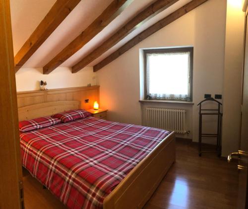 1 dormitorio con 1 cama con manta de cuadros roja en Casa Crepaz, en Canal San Bovo