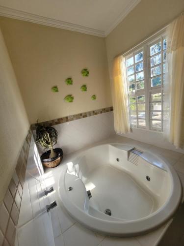 a large white tub in a bathroom with a window at Chalés Sitio Dois Lagos - Amparo SP in Amparo