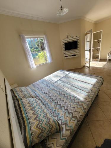a large bed in a bedroom with a window at Chalés Sitio Dois Lagos - Amparo SP in Amparo