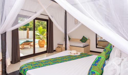 a bedroom with a bed and a view of a pool at Daima Villas in Jambiani