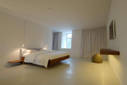 a white bedroom with a bed and a window at B&B Opus35 in Montzen