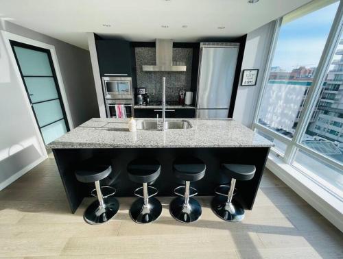 a kitchen with a counter with stools around it at Deluxe 2 bedroom suite downtown free parking with pool and Air Conditioning in Victoria