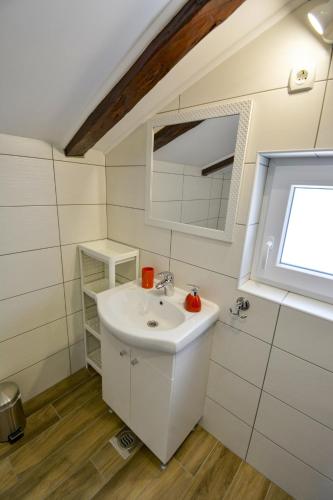 ein Badezimmer mit Waschbecken und Spiegel in der Unterkunft Apartmani Kordić in Rab