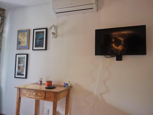 a flat screen tv hanging on a wall with a table at George's rooms in Stari Grad