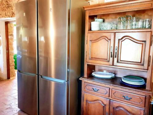 a kitchen with a stainless steel refrigerator and wooden cabinets at Masía para grupos con piscina privada28 pax in Girona