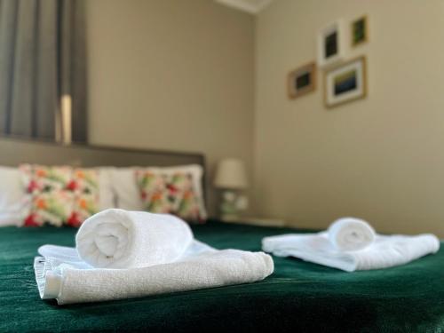 two towels sitting on a bed with a green blanket at ROYAL GREEN Apartamenty Deptak in Karpacz