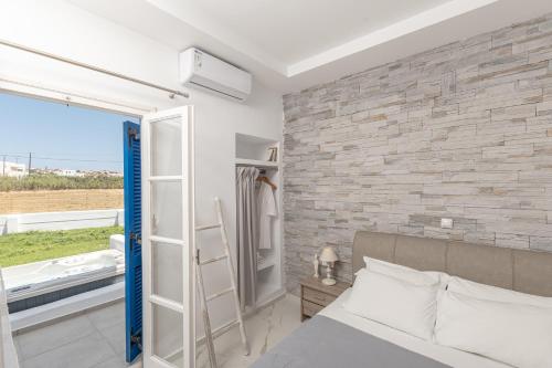 a bedroom with a brick wall and a bed and a window at Dimitra Hotel in Agios Prokopios