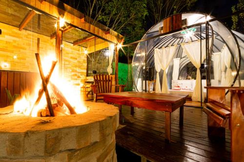 eine Terrasse mit einer Feuerstelle und einem Holztisch in der Unterkunft Pousada Chale Luiz in Santo Antônio do Pinhal