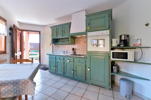 - une cuisine avec des armoires vertes et une table dans une pièce dans l'établissement s'Harzala Vert, à Bergheim