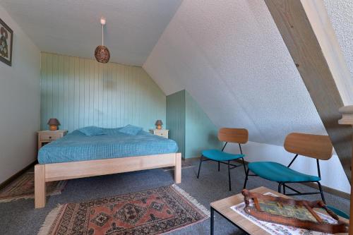 a bedroom with a bed and two chairs and a table at s'Harzala Vert in Bergheim