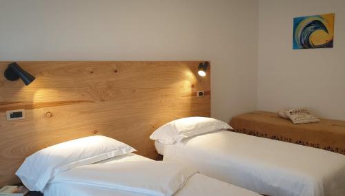 a bedroom with two white beds and a wooden headboard at Anima Franca Bed and breakfast in Greve in Chianti