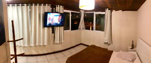 uma sala de estar com uma televisão e uma janela em Pousada Cantinho do Joá no Rio de Janeiro