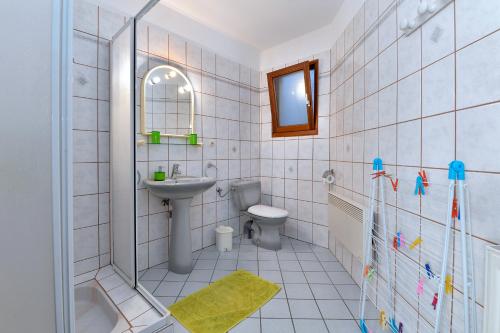 a white tiled bathroom with a sink and a toilet at S'Harzala Vert bis in Bergheim
