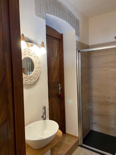 een badkamer met een wastafel, een spiegel en een douche bij AGRITURISMO MODOLO Belluno Dolomiti in Belluno