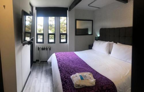 1 dormitorio con 1 cama grande con manta morada en Posada LA MARIÑERA, en Tibasosa