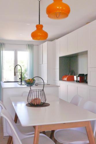 - une cuisine avec une table, des chaises et des lampes orange dans l'établissement Sacré Coeur d'Ambrussum, à Lunel