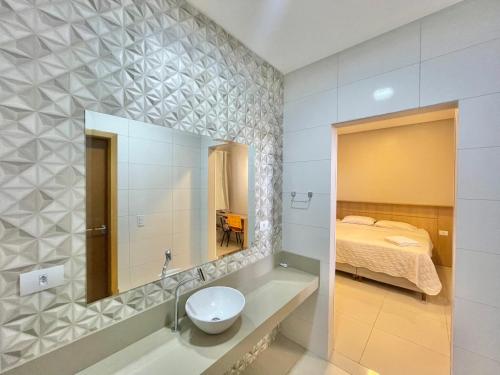 a bathroom with a sink and a mirror and a bed at Hotel Armenia in Cascavel